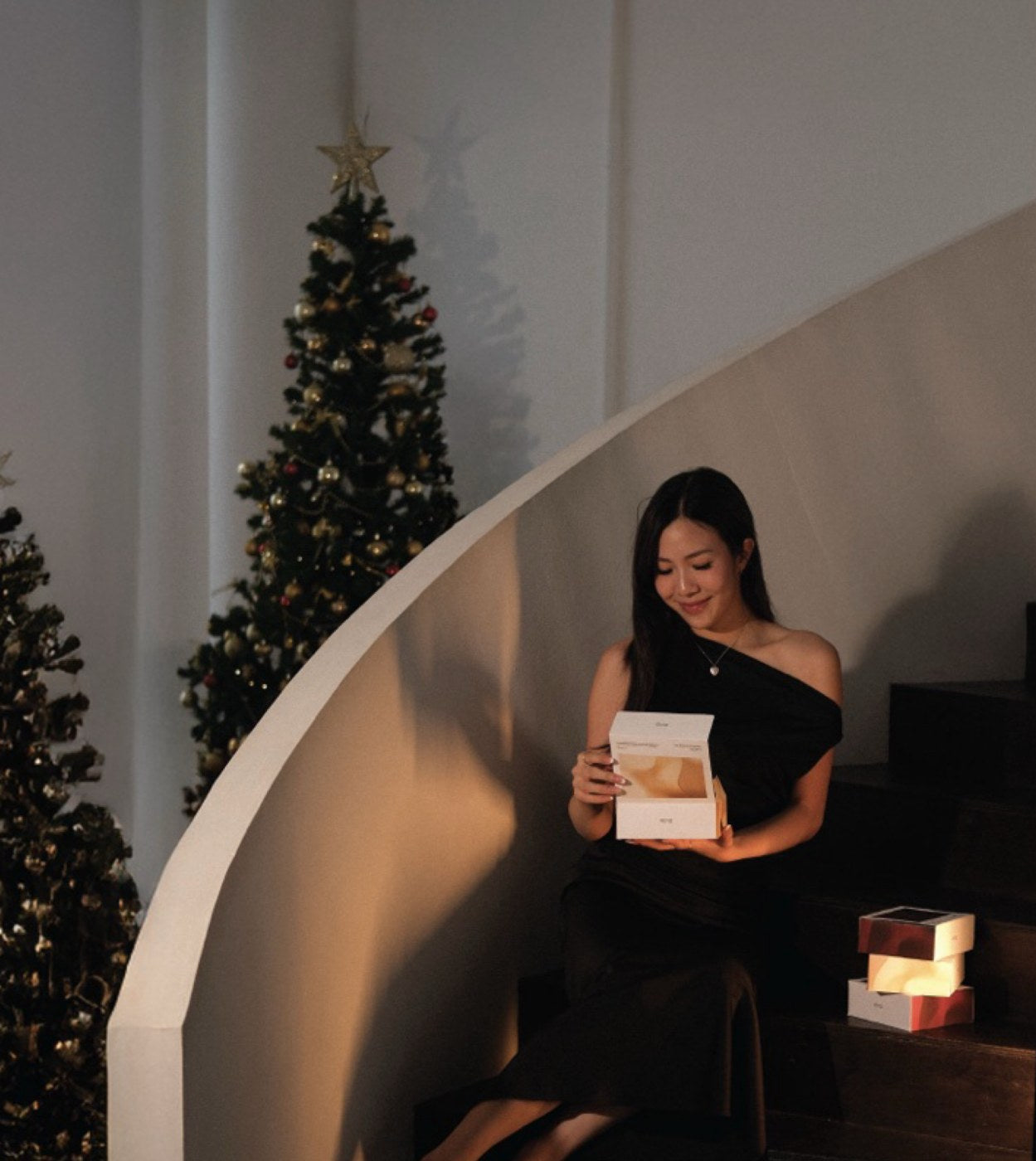 A guest opening a VE/LA gift by the tree